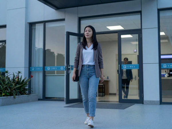 Female anesthesiologist leaving a hospital building at dawn after a long overnight shift